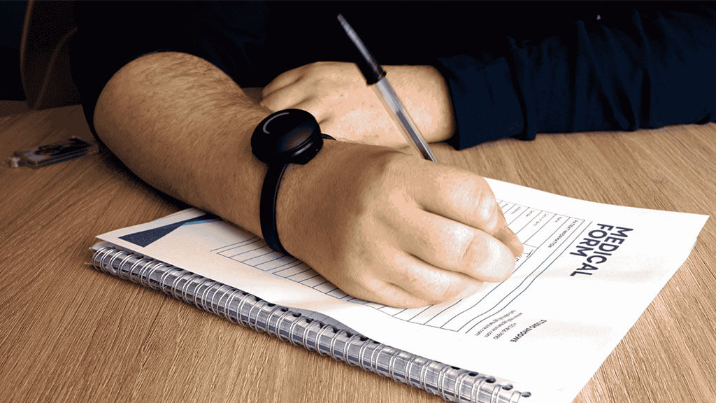 Closeup of a Clickscape button on a man's wrist as he writes notes