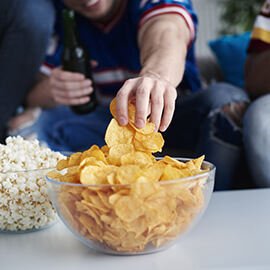 Sports fan reaching hand into a bowl of chips